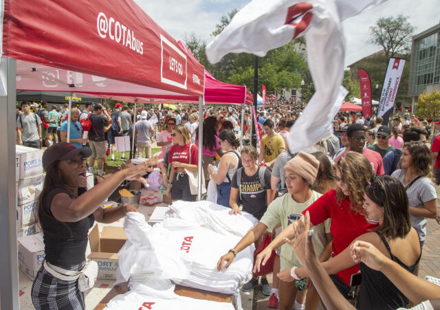 A person hands out free t-shirts at the Cota Bus stand.